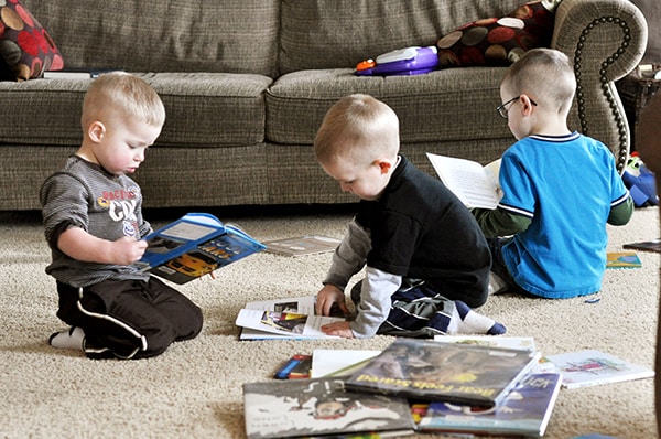 Three little boys reading on the floor.