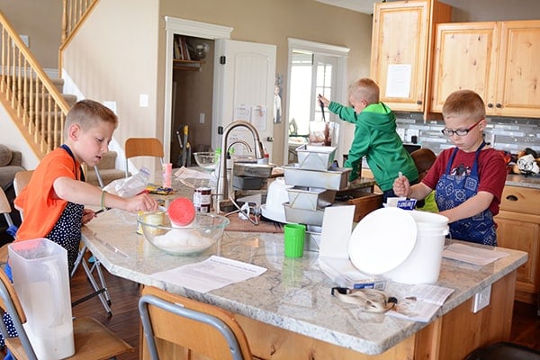 Three little boys all cooking in a kitchen together. 