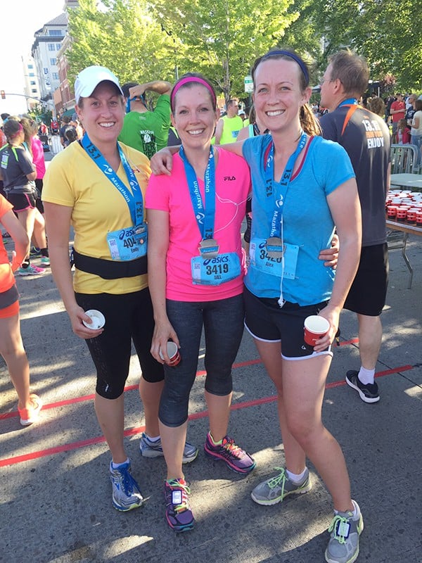 Three woman with race medals around their neck. 