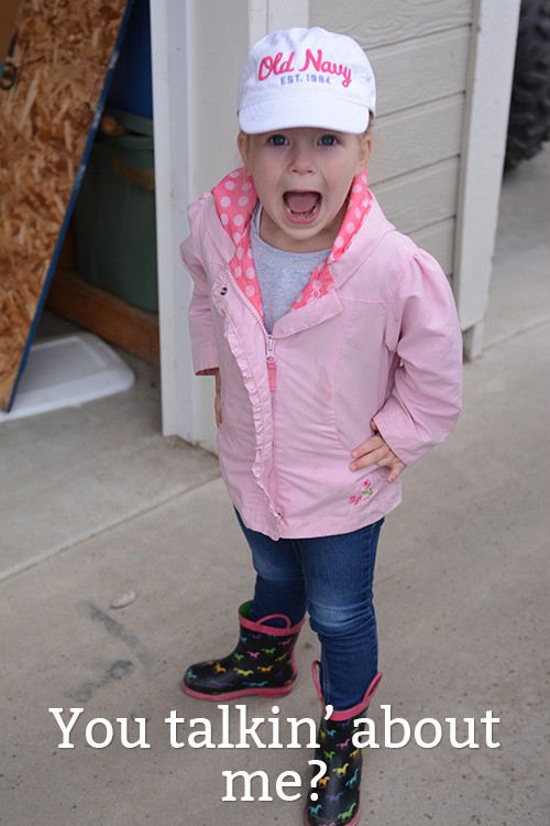 A little girl in a pink jacket and white hat. 