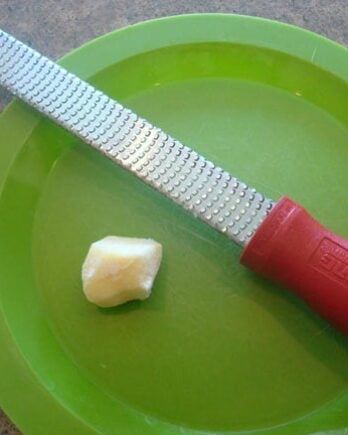 a microplane and a chunk of fresh ginger on a green plate