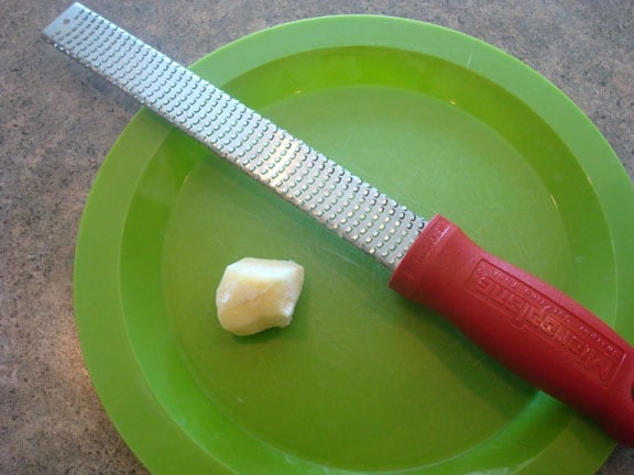 a microplane and a chunk of fresh ginger on a green plate