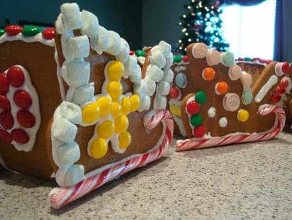 Two gingerbread sleds decorated with candy canes and candy on a countertop.