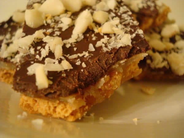 Chocolate toffee with almonds on top on a white plate.