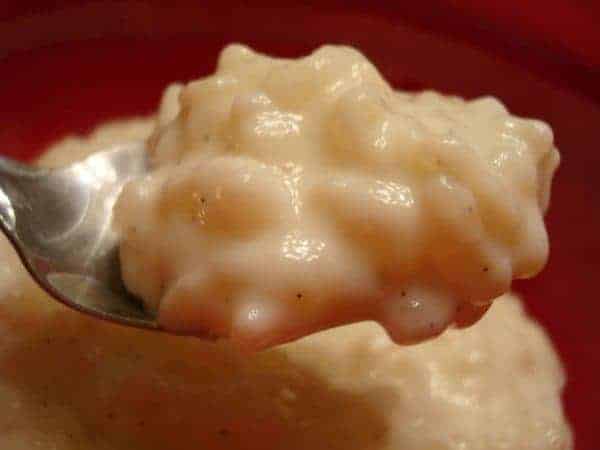 A spoonful of rice pudding over a bowl of rice pudding.