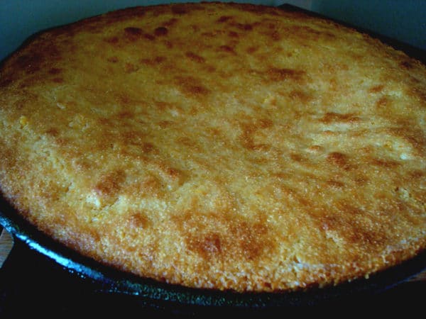 A dark skillet filled with baked cornbread.