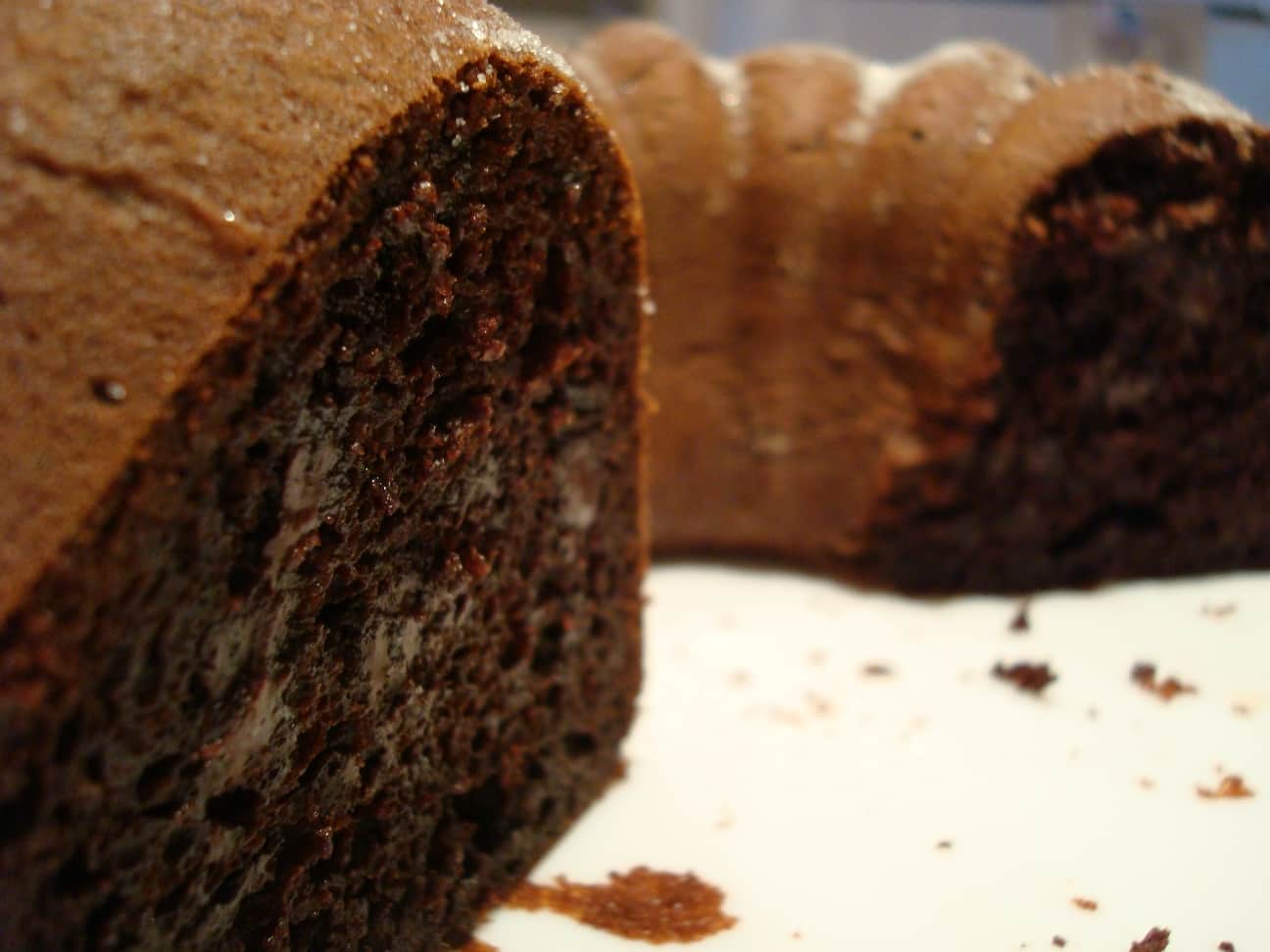 a chocolate bundt cake with a slice taken out on a white plate
