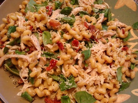 Pasta salad with spinach and tomatoes mixed in.