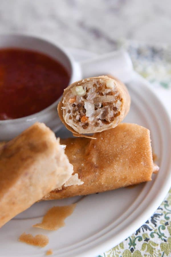 An egg roll split in half on a white plate.