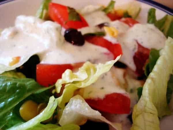 Green salad with sliced tomatoes and dressing.