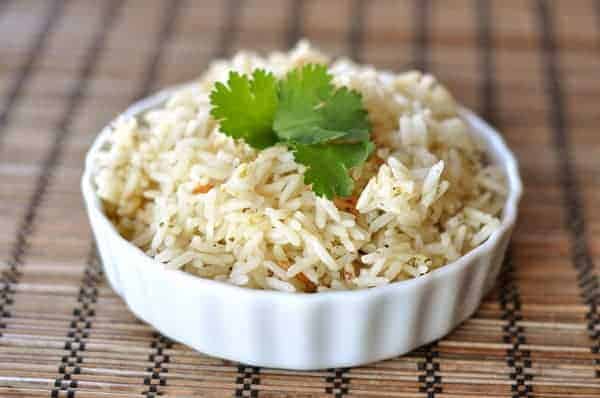 A white ramekin filled with cooked rice and topped with cilantro.