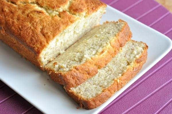 Loaf of banana bread with two slices cut on a white plate.