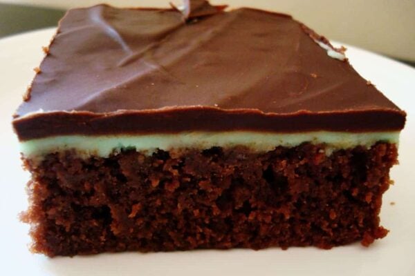 Chocolate frosted brownie on a white plate.