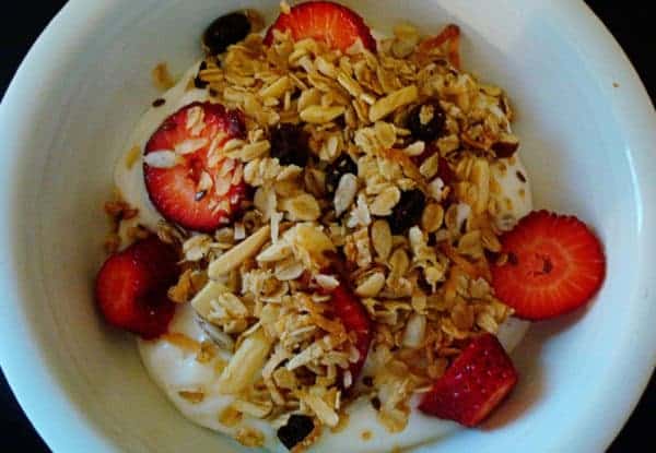 Granola, strawberries, and yogurt in a white bowl.