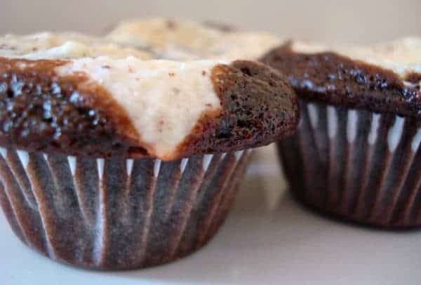 Two black and white cupcakes on a white plate.