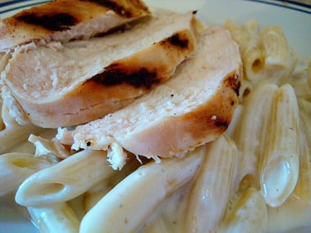 Pasta and slices of grilled chicken on a plate.