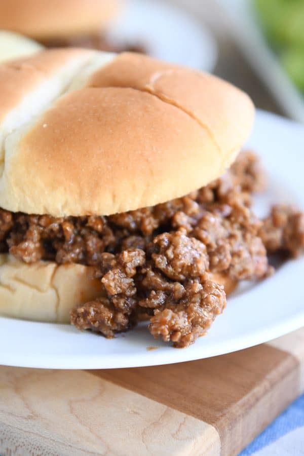 sloppy joe meat spilling over bun onto white plate