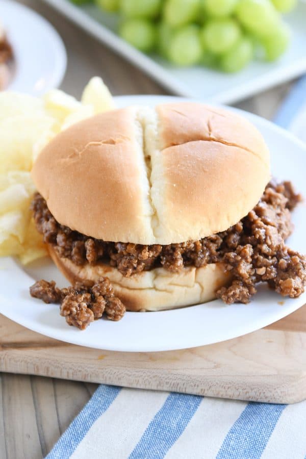 Sloppy joe with meat spilling out, on a white plate.