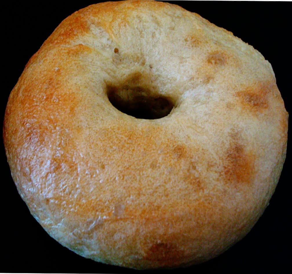 Homemade bagel on a black plate.