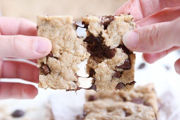 pulling apart two halves of a warm oatmeal chocolate chip coconut cookie bar