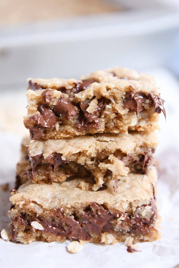 Stack of three oatmeal chocolate chip coconut cookie bars on white napkin.