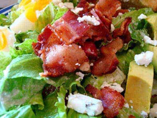 Salad with bacon, avocado, egg, and feta cheese.