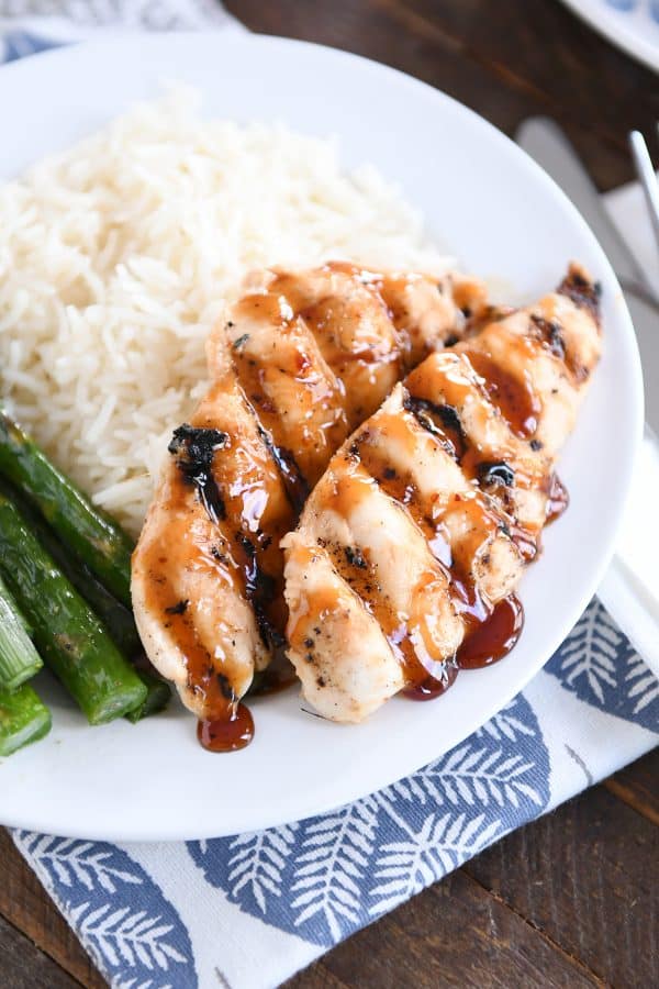 Sticky coconut chicken on white plate with coconut rice and asparagus.
