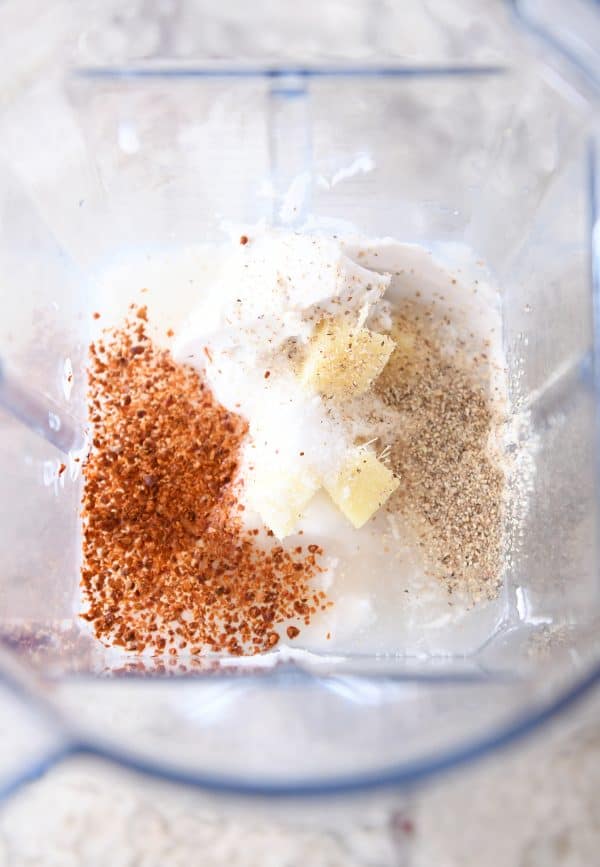 Top down view of a blender full of spices and fresh ginger chunks.