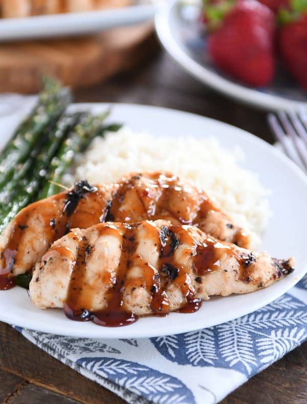 Sticky coconut chicken on white plate with coconut rice and asparagus.