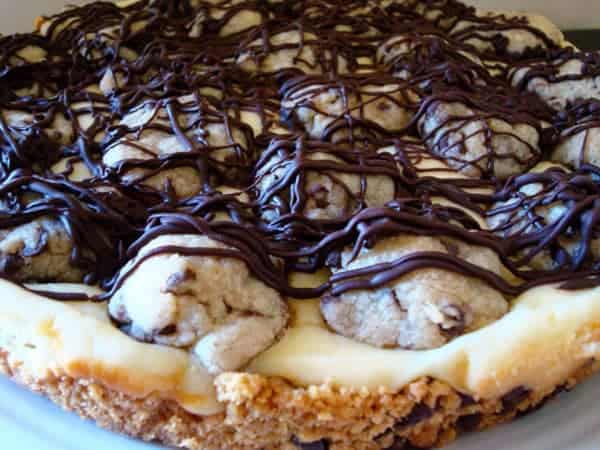 Cookie crust with cheesecake middle and cookie dough balls and chocolate drizzle on top.