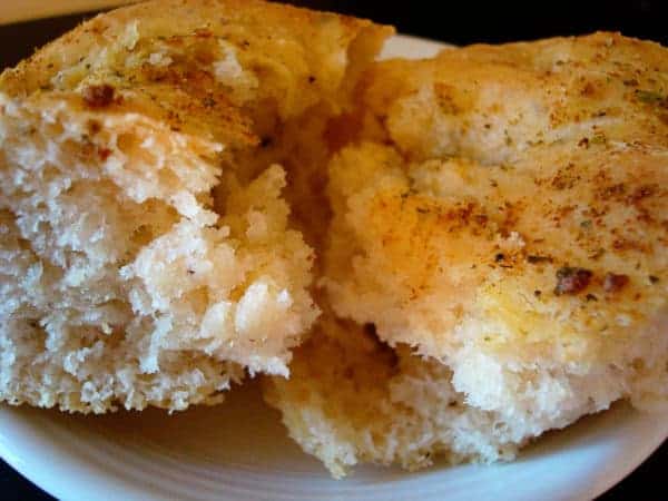 Two pieces of herb-coated bread on a white plate.