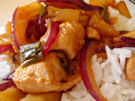 Chicken with pineapple and red onion slices on white rice.