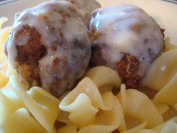 cream sauce covered meatballs on pasta