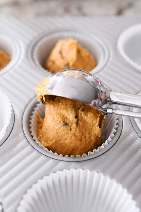 Scooping muffin batter into muffin liners.