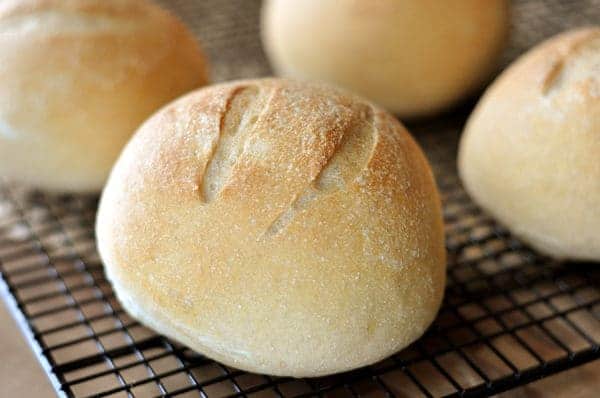 Golden brown bread bowls on a cooling rack.