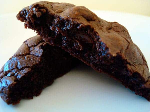 Chocolate cookie split in half on a white plate.