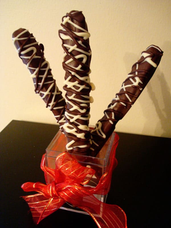 three chocolate dipped pretzel rods drizzled with white chocolate