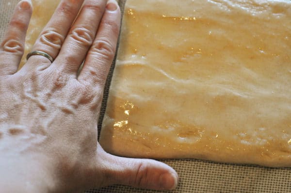 hand making an l-shape on top of rolled out bread dough