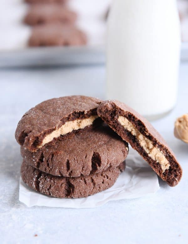 Stack of chocolate peanut butter stuffed cookies with top cookie broken in half.