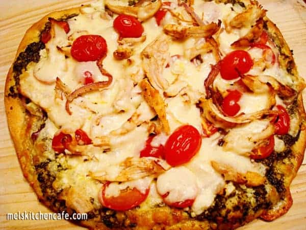 Pesto pizza with chicken and tomatoes on top.