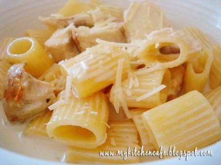 Tube pasta with shredded parmesan in a white bowl.