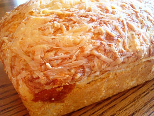 Loaf of cooked bread covered with melted cheese.