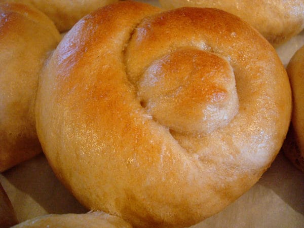 A golden brown baked roll shaped like a knot.