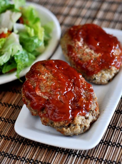 Two mini glazed meatloaves on a white plate.
