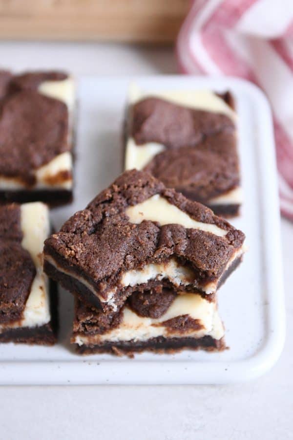Stack of black and white cheesecake brownies with bite taken out of top.