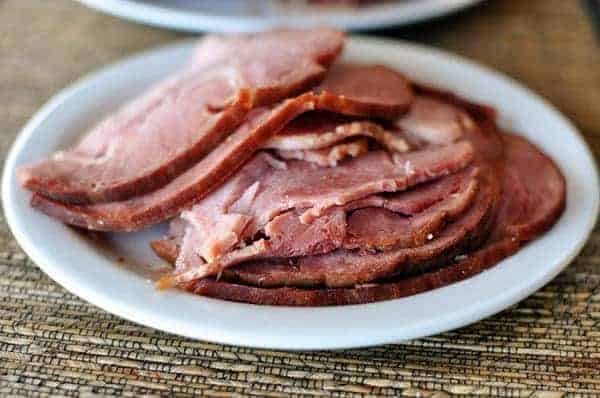 A white plate full of sliced ham.