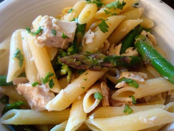 Pasta with tuna and asparagus in a white bowl.