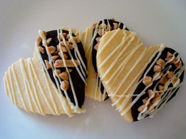 Three heart shaped chocolate dipped sugar cookies drizzled in white chocolate.