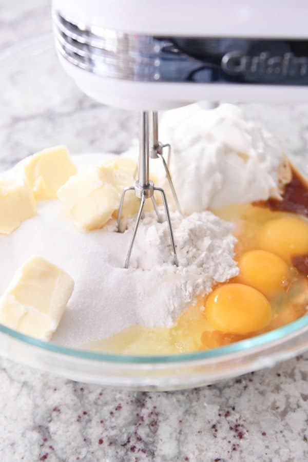 mixing all the ingredients for chocolate chip cake batter with handheld mixer