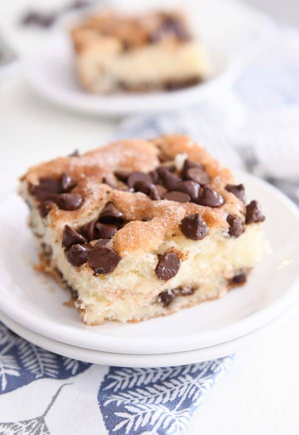 Square slice of chocolate chip cake on white plate.